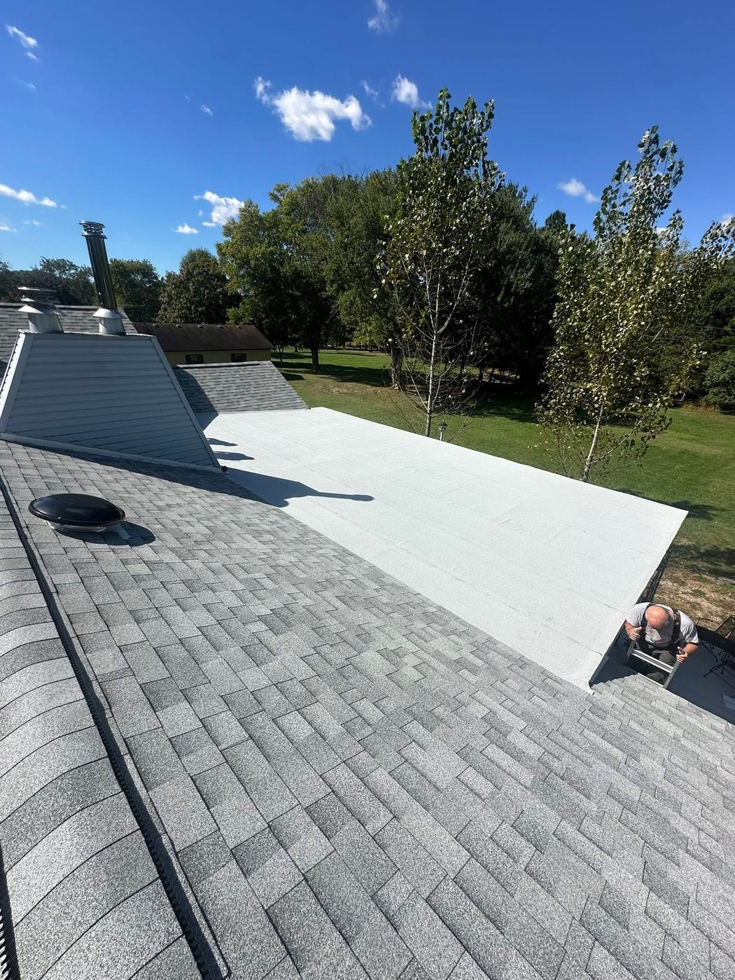 Roof replacement project with new shingles and low-slope roofing area