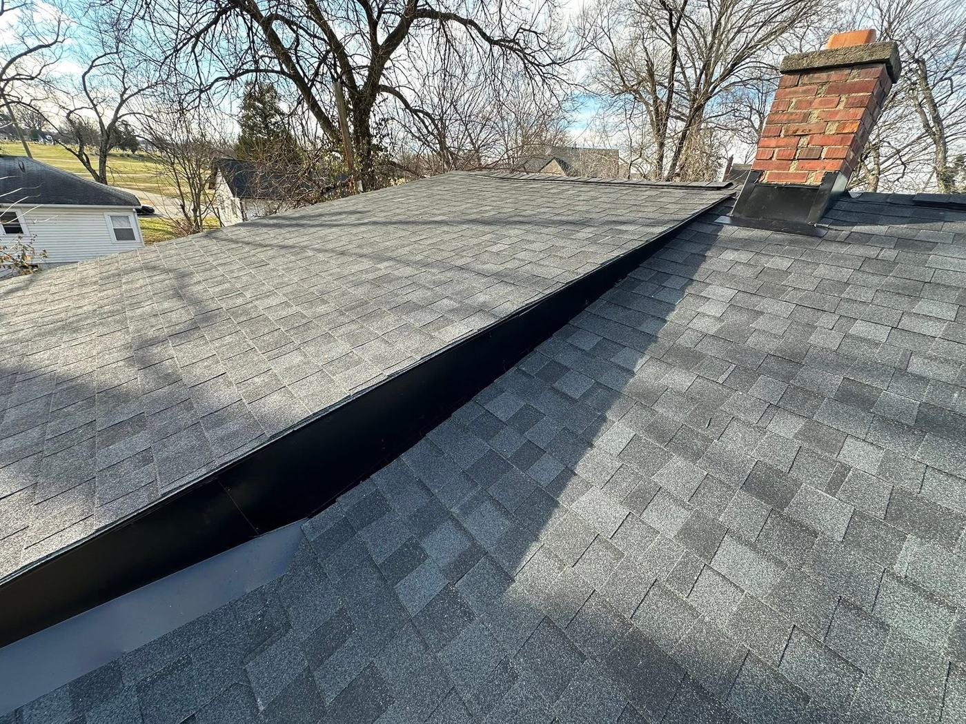 Gray residential shingle roof with chimney flashing detail